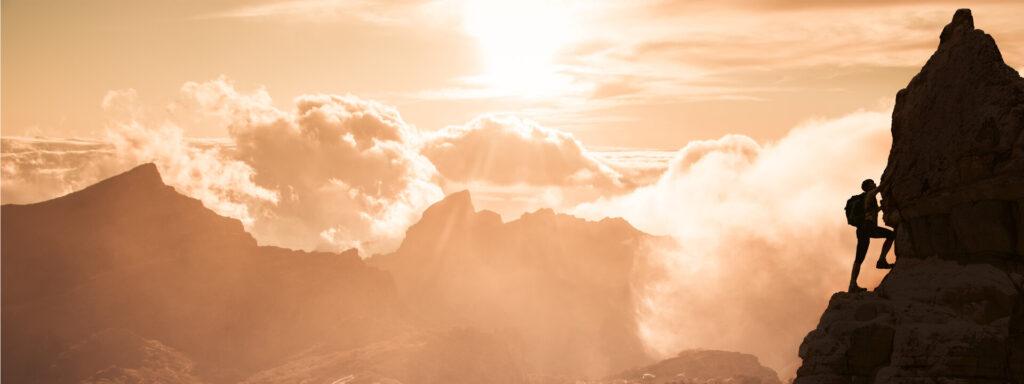 Silhouette einer erfolgreich kletternden Frau in den Bergen, bei schönem Sonnenuntergang. Konzept der Bewegungsmotivationsinspiration