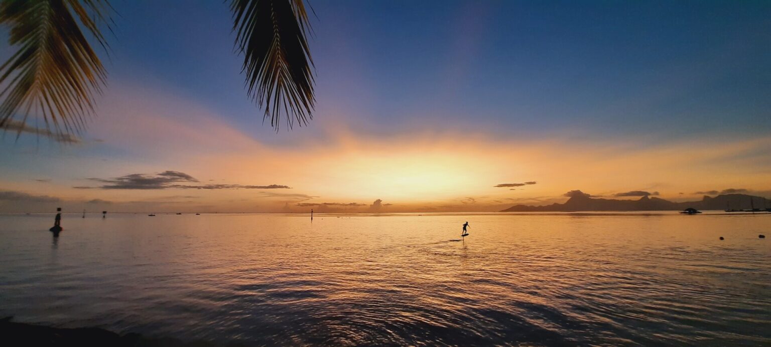 Mann schwebt auf E-Surfboard, einem Awake Board, über das Wasser bei Sonnenuntergang