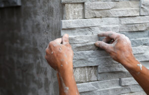 Trockenbauer installieren Steinwandoberfläche mit Zement außen am Haus